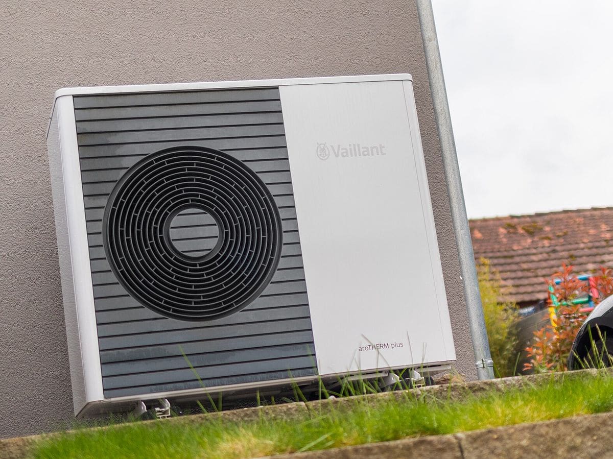 Buitenunit van een warmtepomp naast een woning