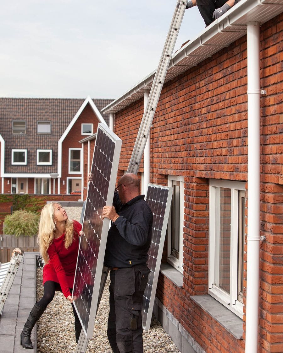 Installateurs dragen een zonnepaneel naar het dak